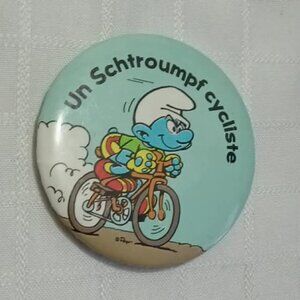 Strange & unusual vintage button pin featuring "un schtroumphf cycliste"